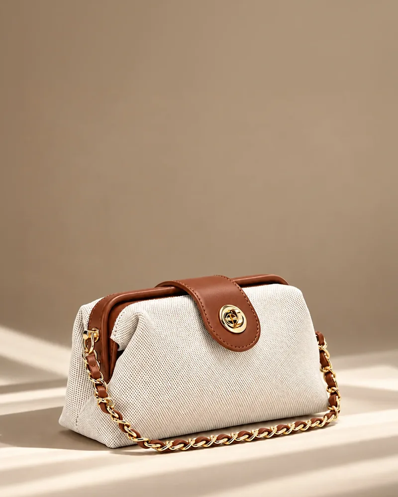 Canvas frame bag with tan leather trim and chain-link handle